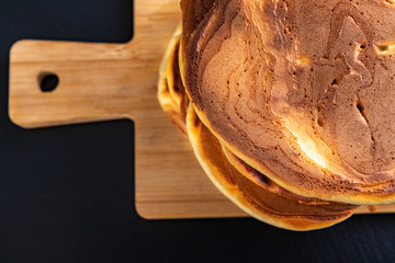 Pile of fresh pancakes on a wooden board. Tasty cookies on the kitchen table.