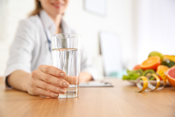 Canvas Print - Nutritionist with glass of water at desk in office, closeup