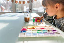 Young Girl Painting Colorful Wooden Doll Models Of Her Family