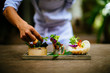 © Mint Images - Close up of chef putting the final touches on a dish of salads and spring rolls.,Saigon