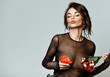 Portrait of young beautiful sexy brunette woman in black transparent clothing holding flowers on nipples places