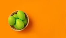 Easter Concept. Simple Composition With Green Eggs In Basket On Vibrant Orange Background