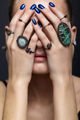 Wall Mural - Young woman with eyes closed and many bijouterie rings with stones on fingers