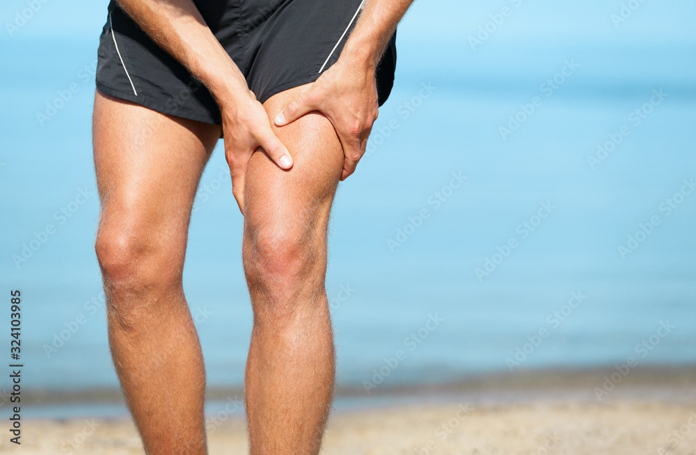 Sports injury muscle cramp pain fit runner man athlete holding painful thigh leg on outdoor summer jogging exercise. Fitness lifestyle. - obrazy, fototapety, plakaty 