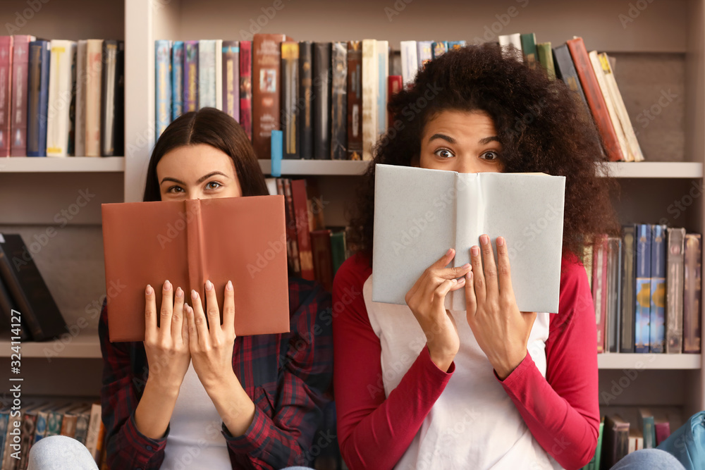 Female students with books preparing for exam in library