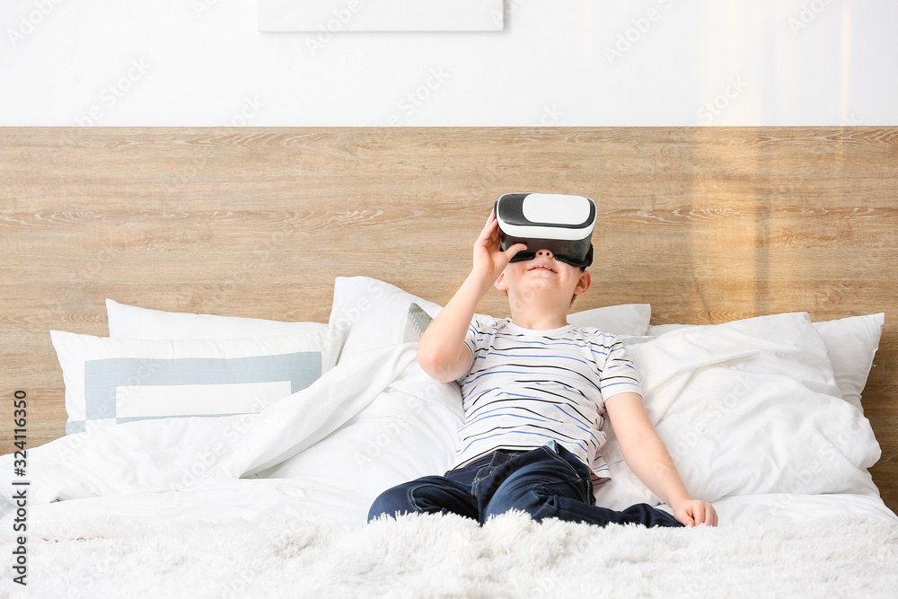 Little boy with virtual reality glasses in bedroom