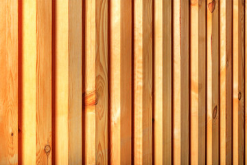 Texture and background of a new natural wooden fence with vertical bars.