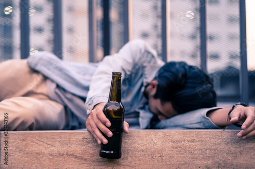 Fotomural Asian drunk man holding beer bottle lying on floor