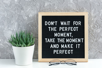 Don't wait for the perfect moment, take the moment and make it perfect. Motivational quote on letter board, succulent flower and glasses on table. Concept inspirational quote of the day