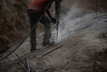 A Construction Worker Drills Onto A Rock Stone At A Site Using A Vacuum Drilling Machine