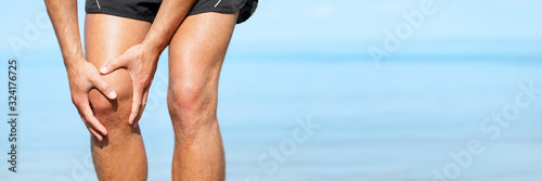 Fotomural Knee pain man with painful sports injury fit runner active man athlete holding leg on outdoor summer jogging exercise panoramic banner