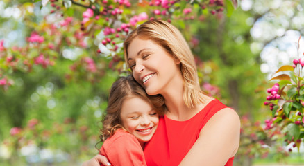 family, motherhood and people concept - happy smiling mother and daughter hugging over cherry blosso