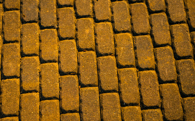 Brick stone paved road surface as texture background toned in warm colors