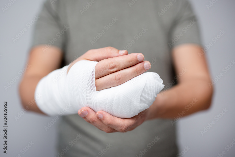 first aid concept - close up of male hand with bandage and gypsum - obrazy, fototapety, plakaty 