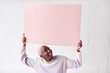 © Monkey Business - Happy Young Woman Holding Blank Pink Card With Copy Space Above Head White Against White Studio Wall