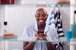 © Monkey Business - View Through Bathroom Cabinet Of Woman Checking Messages On Phone Before Going To Work