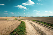 A Long Winding Dirt Road Between Plowed Fields