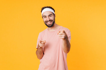 Wall Mural - Image of muscular athletic young man smiling and pointing fingers