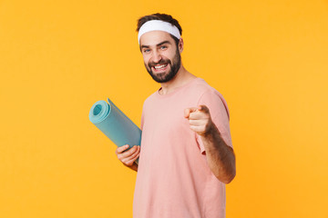 Canvas Print - Image of muscular athletic young man smiling and carrying fitness mat