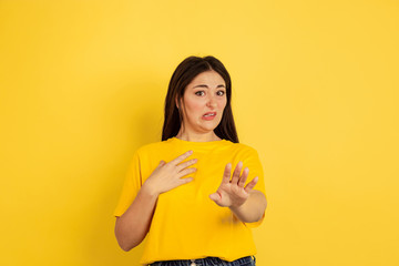 Wall Mural - Disguasted. Caucasian woman's portrait isolated on yellow studio background. Beautiful female brunette model in casual style. Concept of human emotions, facial expression, sales, ad, copyspace.