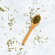 Dried mung beans with a spoon on a white background