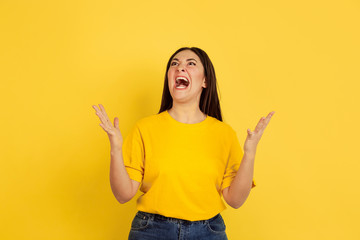 Poster - Angry screaming. Caucasian woman's portrait isolated on yellow studio background. Beautiful female brunette model in casual style. Concept of human emotions, facial expression, sales, ad, copyspace.