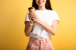 cropped view of smiling girl holding coffee to go on yellow background
