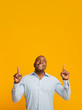 Positive african middle aged man pointing up at free space