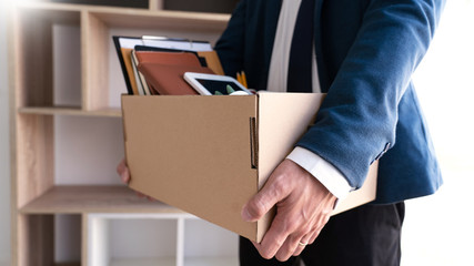 Businessmen are holding resignation document and packing personal company on brown cardboard box changing work, resign concept