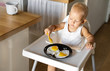 A small child independently eats a fried egg with a fork. Education and upbringing of children, healthy nutrition and childhood.