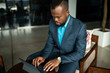 © JonoErasmus - African businessman using a digital tablet in an office lobby
