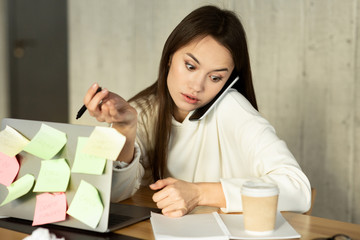 Freelancer girl working, talking on smartphone using laptop