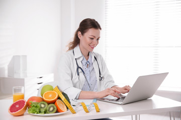 Canvas Print - Nutritionist working with laptop at desk in office