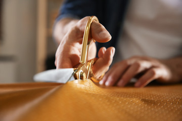 Wall Mural - Man cutting leather with scissors in workshop, closeup