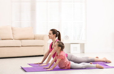 Poster - Young mother with little daughter practicing yoga at home