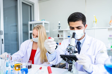 Two scientists are working holding looking at test tube with sample in a chemistry lab scientist or young female and male researcher are doing investigations in Laboratory analysis background