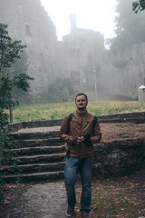 Man walking alone. Fortification on top of the mountain, old castle. Journey. Mystical atmosphere, fog, white haze, mist. Summer day. Second Tower. San Marino, Italy