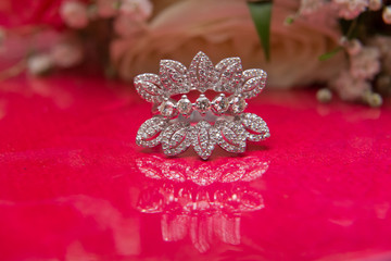 White wedding rings . flower bouquet selective focuse .Two silver wedding rings red background . Romantic and lovely wedding , macro . Bride and groom with Engagement gold rings put on the red table .