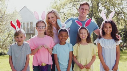 Wall Mural - Portrait Of Parents And Children Wearing Bunny Ears On Easter Egg Hunt In Garden