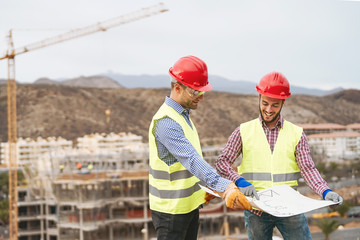 Work engineers discussing about new building area - Young builders reading the project in the construction site - Carpentry teamwork engineering concept