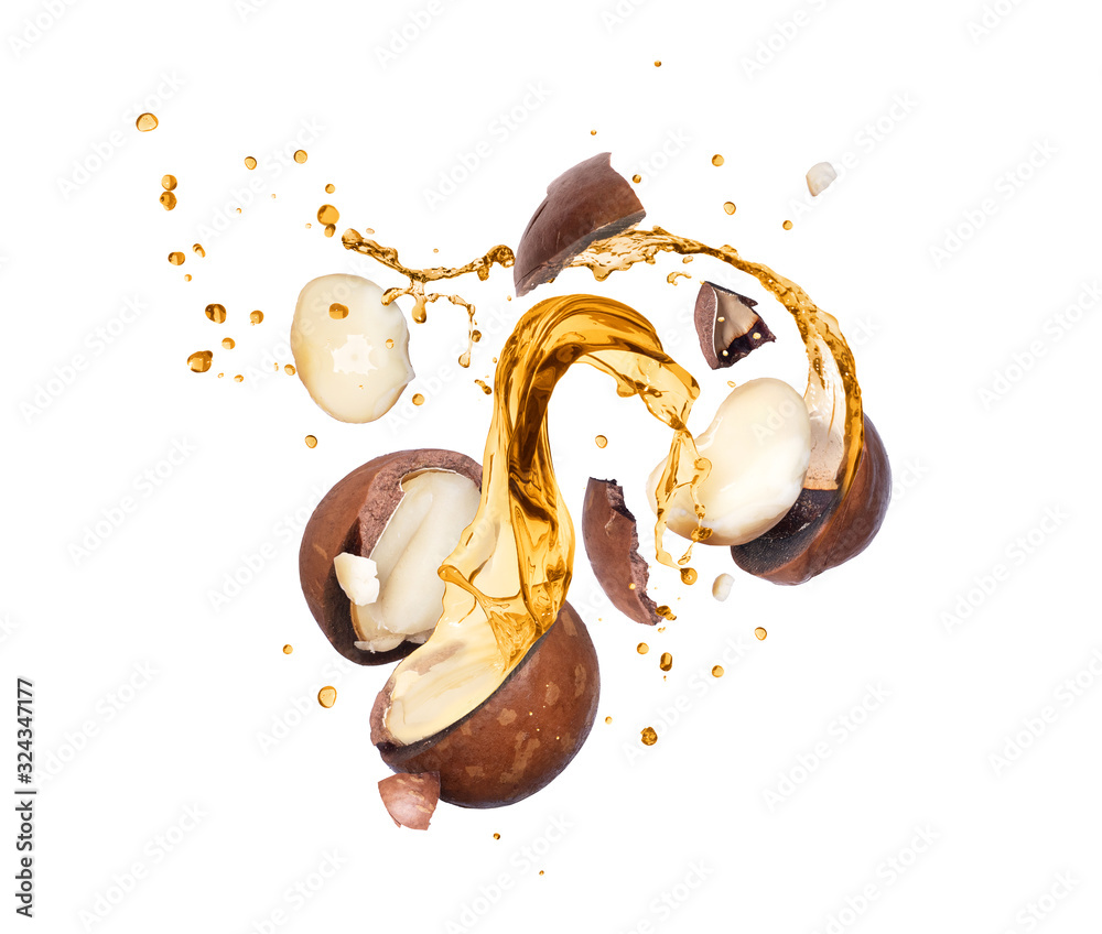Crushed macadamia nuts with splashes of oil in the air, isolated on ...