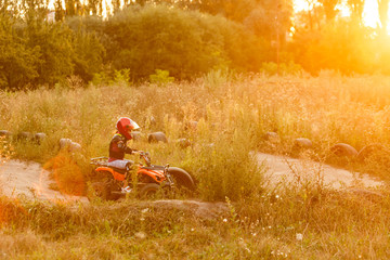 Wall Mural - Happy little girl playing on road at the day time. He driving on quad bike in the park. Child having fun on the nature. Concept of happiness.