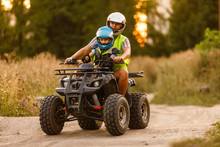 Little Boy With Instructor On A Quad Bike