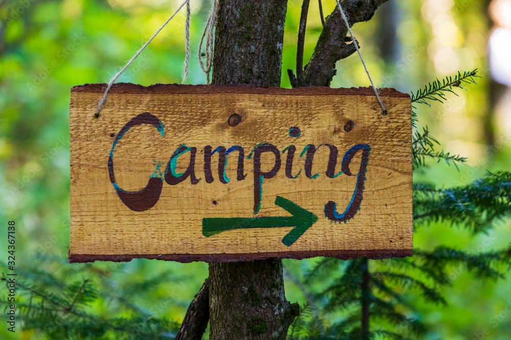 A soft focus closeup view of a handcrafted wood directional campsite sign, woodland camping during multicultural festival celebrating earth and nature - obrazy, fototapety, plakaty 