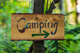 Fototapeta  - A soft focus closeup view of a handcrafted wood directional campsite sign, woodland camping during multicultural festival celebrating earth and nature
