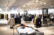 Fashionable clothing store in shopping center. Sale and seasonal change of collection. Led lighting on the ceiling. Fire system and air conditioning system in retail shop. Blurred.