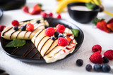 Fototapeta Mapy - Crepes on a plate garnished with berries and mint