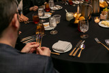 Fototapeta  - Hands holding three forks at a dinner table.