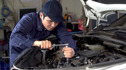 Wall Mural - male mechanic using wrench to repair engine, car service