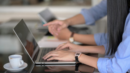 Side view of female typing on laptop while her co-worker briefing on their project